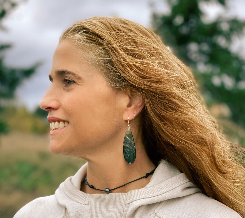 Woman wearing canoe paddle shaped carved mother of pearl earrings